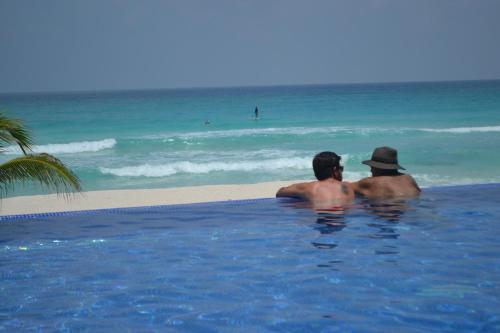 two men sitting in a swimming pool on the beach at Ocean View Condo in Cancún