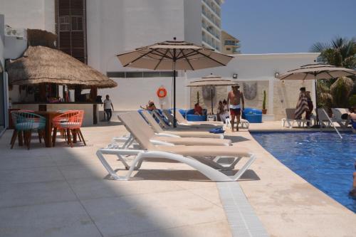a group of chairs and umbrellas next to a pool at Ocean View Condo in Cancún