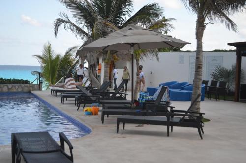 a pool with chairs and an umbrella next to the ocean at Ocean View Condo in Cancún