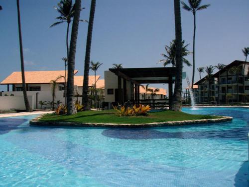 una gran piscina con palmeras y un edificio en Villa 06 - Taiba Beach Resort - TBR, en São Gonçalo do Amarante