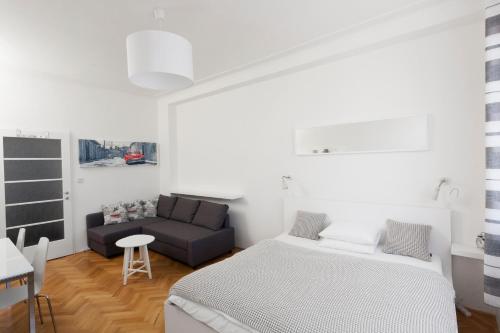 プラハにあるCasa Anna Apartment Opletalovaの白いベッドルーム(ベッド1台、ソファ付)
