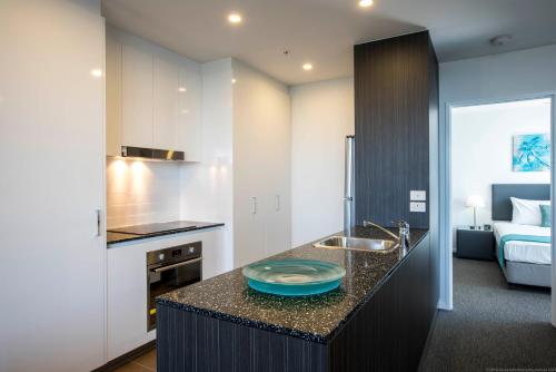 una cocina con fregadero y una cama en una habitación en Synergy Broadbeach - Official, en Gold Coast