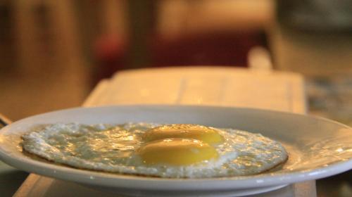 a fried egg on a plate on a table at D'MAX Hotel & Convention Lombok in Praya