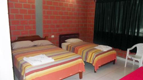two beds in a room with a brick wall at Hotel Ambaibo in Rurrenabaque