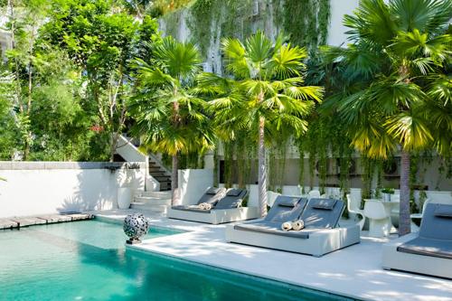 a resort pool with lounge chairs and palm trees at Petitenget 501 in Seminyak
