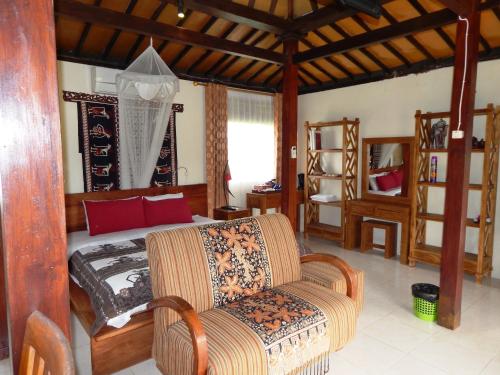 a bedroom with a bed and a chair in it at Alamanda Family Villas, Pool & Local Tours in Yogyakarta