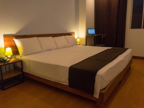 ein Schlafzimmer mit einem großen Bett mit zwei Lampen und einem TV in der Unterkunft Central Bed & Breakfast in Iquitos