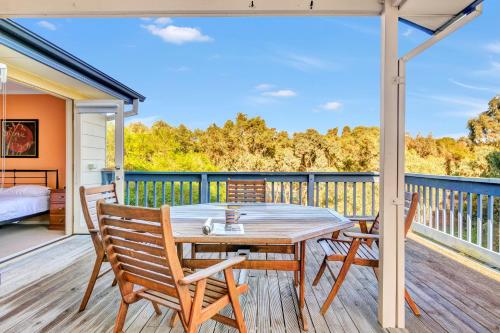 a wooden table and chairs on a deck with a bed at All Decked Out - Port Willunga - C21 SouthCoast Holidays in Port Willunga