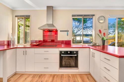 a kitchen with white cabinets and red countertops at All Decked Out - Port Willunga - C21 SouthCoast Holidays in Port Willunga