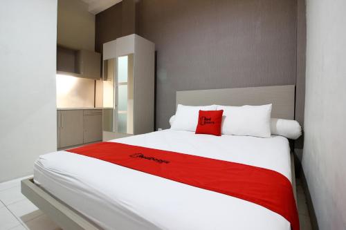 a bedroom with a large white bed with a red blanket at RedDoorz Plus near UPN Jogjakarta 2 in Yogyakarta