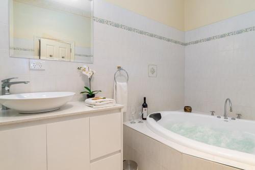 a white bathroom with a tub and a sink at Barossa Vineyard Cottages in Bethany