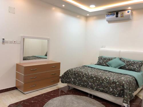 a bedroom with a bed and a dresser and a mirror at Kendah Chalet in Buraydah