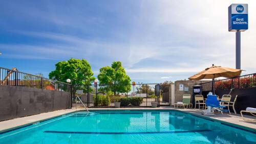 uma piscina com guarda-sol e cadeiras em Best Western Willows Inn em Willows