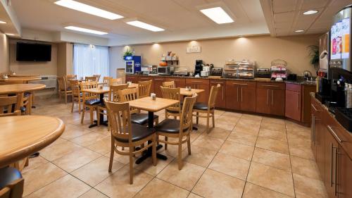 a restaurant with tables and chairs and a kitchen at Best Western Clifton Park in Clifton Park