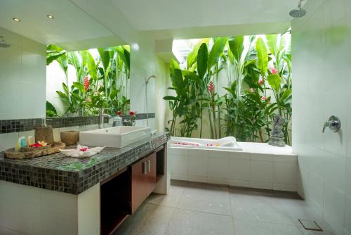 a bathroom with a sink and a tub with plants at Arama Riverside 5 Bedrooms by Villas Direct Bali in Legian