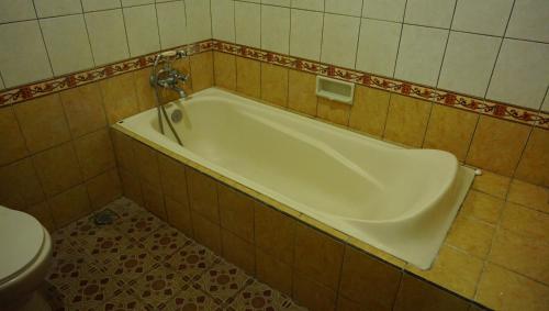a bath tub in a bathroom with a toilet at Nyuh Gading Accommodation Ubud in Ubud