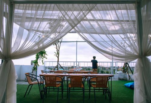 a table with chairs and a man standing in a tent at Deva Bali Apartement in Kerobokan