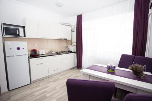 ママイアにあるDeea Apartment Mamaia Nordのキッチン(白いキャビネット、紫色の椅子、テーブル付)