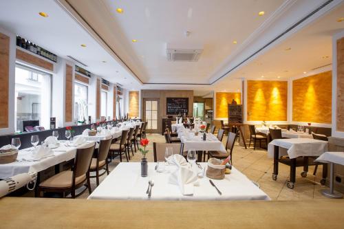 een eetkamer met witte tafels en stoelen bij Hotel an der Oper in München