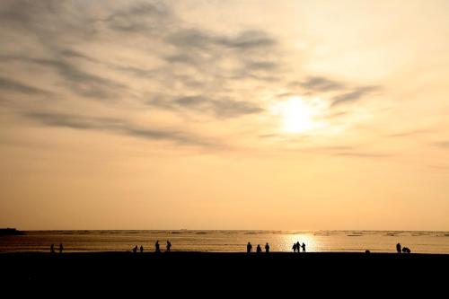 a group of people standing on the beach at sunset at 安平72號民宿 in Tainan