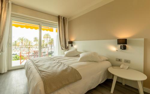 a bedroom with a bed and a table and a window at La Dolce Vita Hotel in Menton