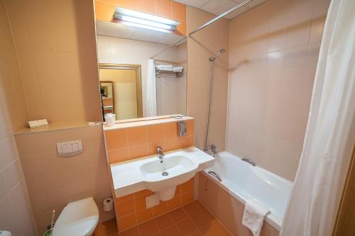 a bathroom with a sink and a toilet and a mirror at Hotel Rychło in Bogatynia