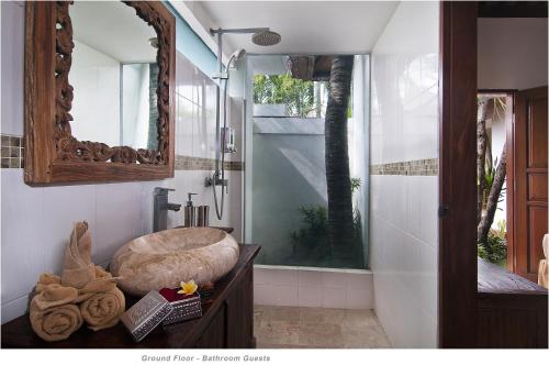 ein Badezimmer mit Waschbecken und Dusche mit Spiegel in der Unterkunft 2BR Villa Senin - Minggu Villas Seminyak in Seminyak