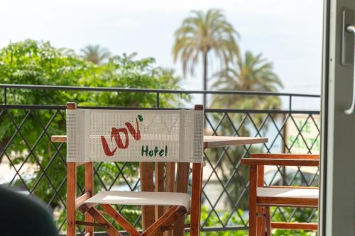 a sign that says joy had sitting on a chair on a balcony at La Dolce Vita Hotel in Menton