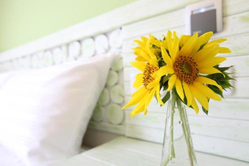 a vase filled with yellow flowers sitting next to a bed at 安平72號民宿 in Tainan