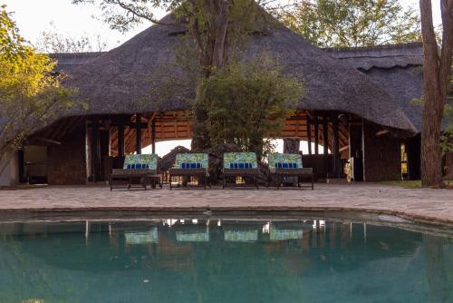 a pavilion with benches and a pool of water at Masuwe Lodge in Victoria Falls