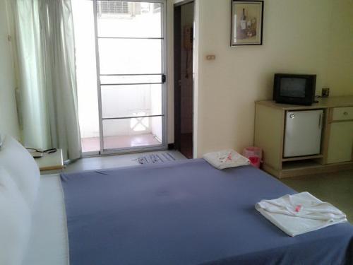 a bedroom with a blue bed and a television at M In Korat Service Apartment in Nakhon Ratchasima