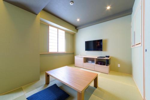 a living room with a wooden table and a tv at Best Western Plus Hotel Fino Chitose in Chitose