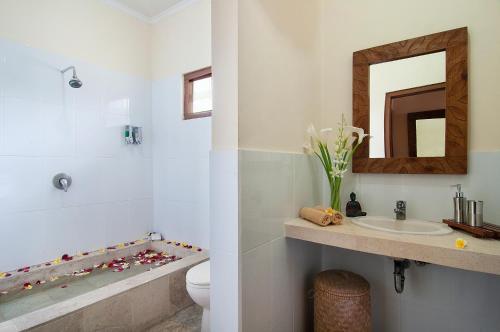 スミニャックにある4BR Villa Selasa - Minggu Villas Seminyakの洗面台、トイレ、鏡のあるバスルーム