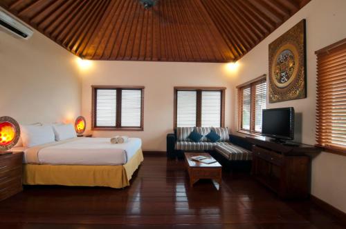 a bedroom with a bed and a couch and a tv at 4BR Villa Selasa - Minggu Villas Seminyak in Seminyak