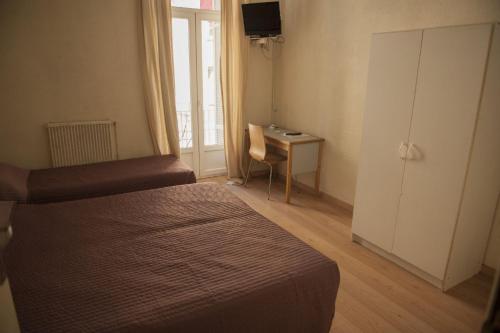 a bedroom with a bed and a desk with a window at Hotel du Palais in Ajaccio