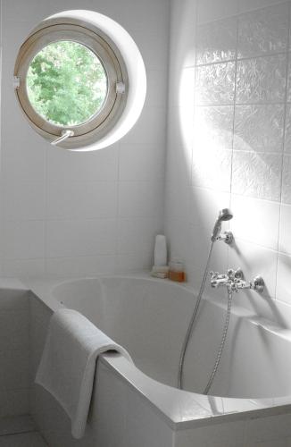 a white bathroom with a tub and a window at Clos Mirabel Manor - Holiday rental in Jurançon