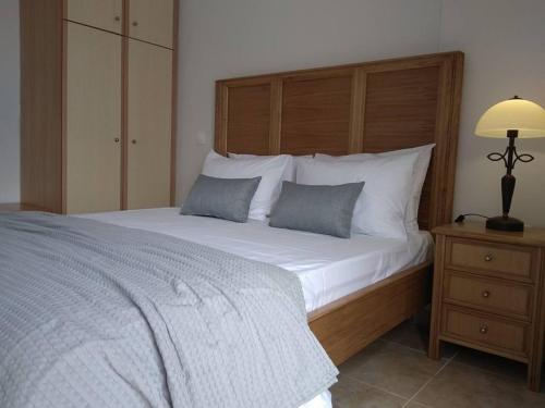 a bedroom with a large bed with a wooden headboard at Three Graces Holiday Houses Complex in Laganas
