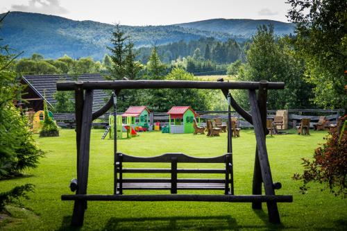 a bench in a park with a playground at Hotel Carpatia Bieszczadzki Gościniec in Wetlina