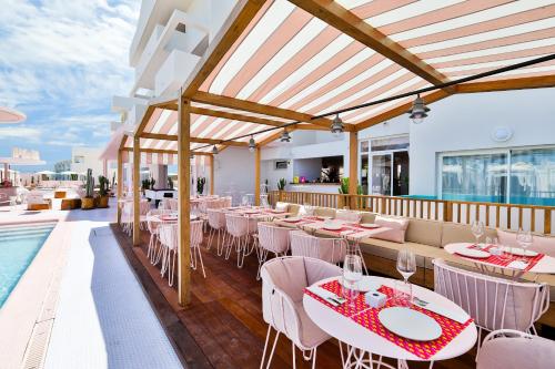 a restaurant with tables and chairs and a swimming pool at Paradiso Ibiza Art Hotel - Adults Only in San Antonio Bay