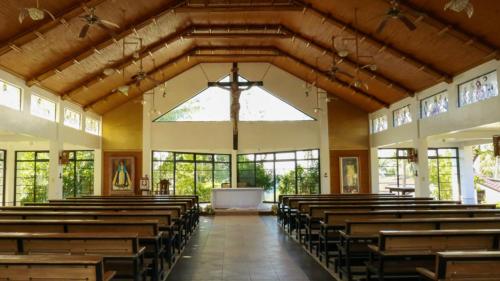 an empty church with wooden pews and a large window at The Duyan House at Sinagtala Resort in Orani