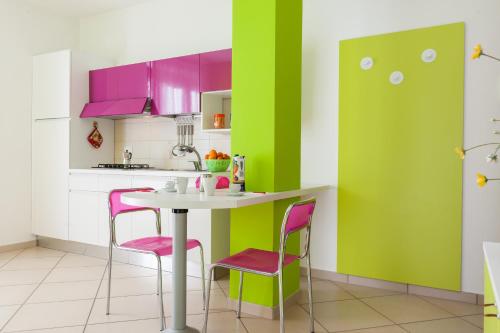 a kitchen with pink and green walls and a table and chairs at Settessenze Residence & Rooms in Agropoli