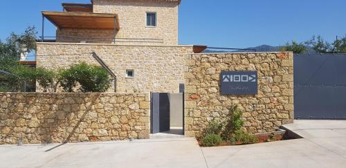 a building with a stone wall with a sign on it at Lithos Guesthouse Kardamili in Kardamili