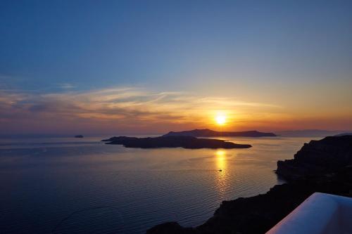 a sunset over a body of water with a island at Volcano View by Caldera Collection in Fira