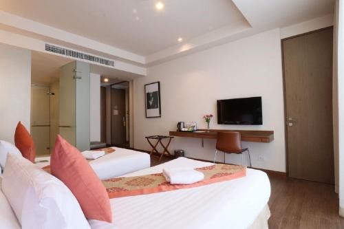 a hotel room with two beds and a television at On 8 Sukhumvit Nana Bangkok by Compass Hospitality in Bangkok