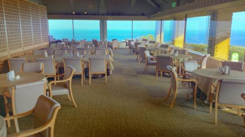 a dining room with tables and chairs and windows at The Southern Links Resort Hotel in Yaese
