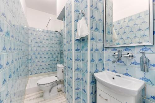 a blue tiled bathroom with a toilet and a sink at Meduza Sopot in Sopot