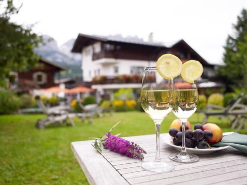 dois copos de vinho e um prato de fruta numa mesa em Landhaus Kaiserblick em Ellmau