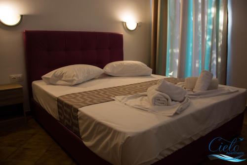 a bed with towels and pillows on it at Cielo Apartments in Poros