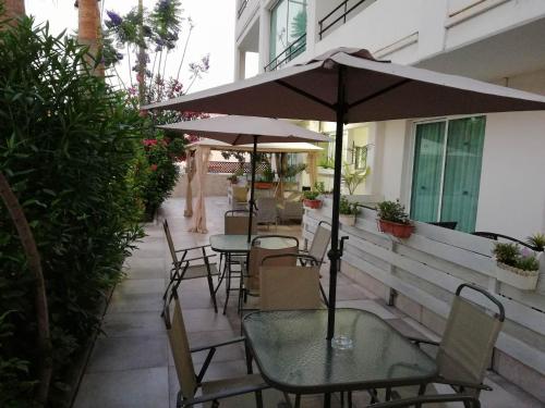 a patio with tables and chairs and an umbrella at Marianna Hotel Apartments in Limassol
