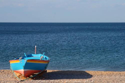 a boat sitting on the beach next to the water at B&B La Rosa dei Venti in Acri